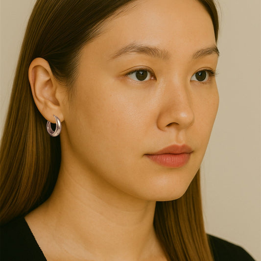 Close-up of Hermin's Eclipse Silver Dome Huggie Hoops in sterling silver with rhodium finish, crafted for elegance and durability