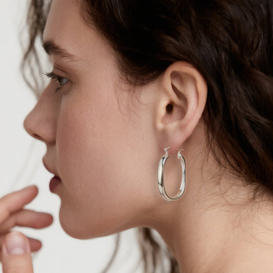 Close-up of Hermin's Classic Statement Oval Silver Hoops - Milan in sterling silver with rhodium finish, crafted for elegance and durability