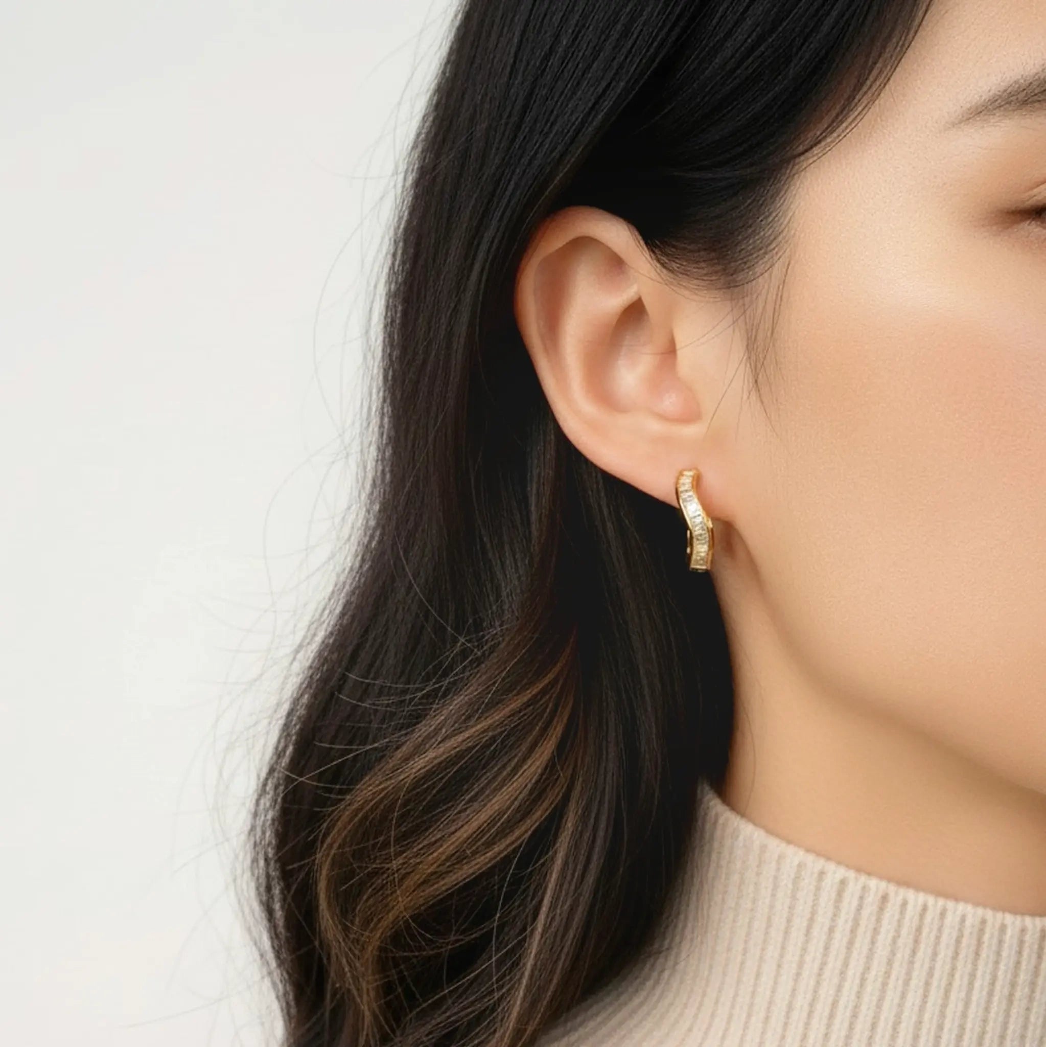 Model wearing gold baguette curve huggie hoop earrings
