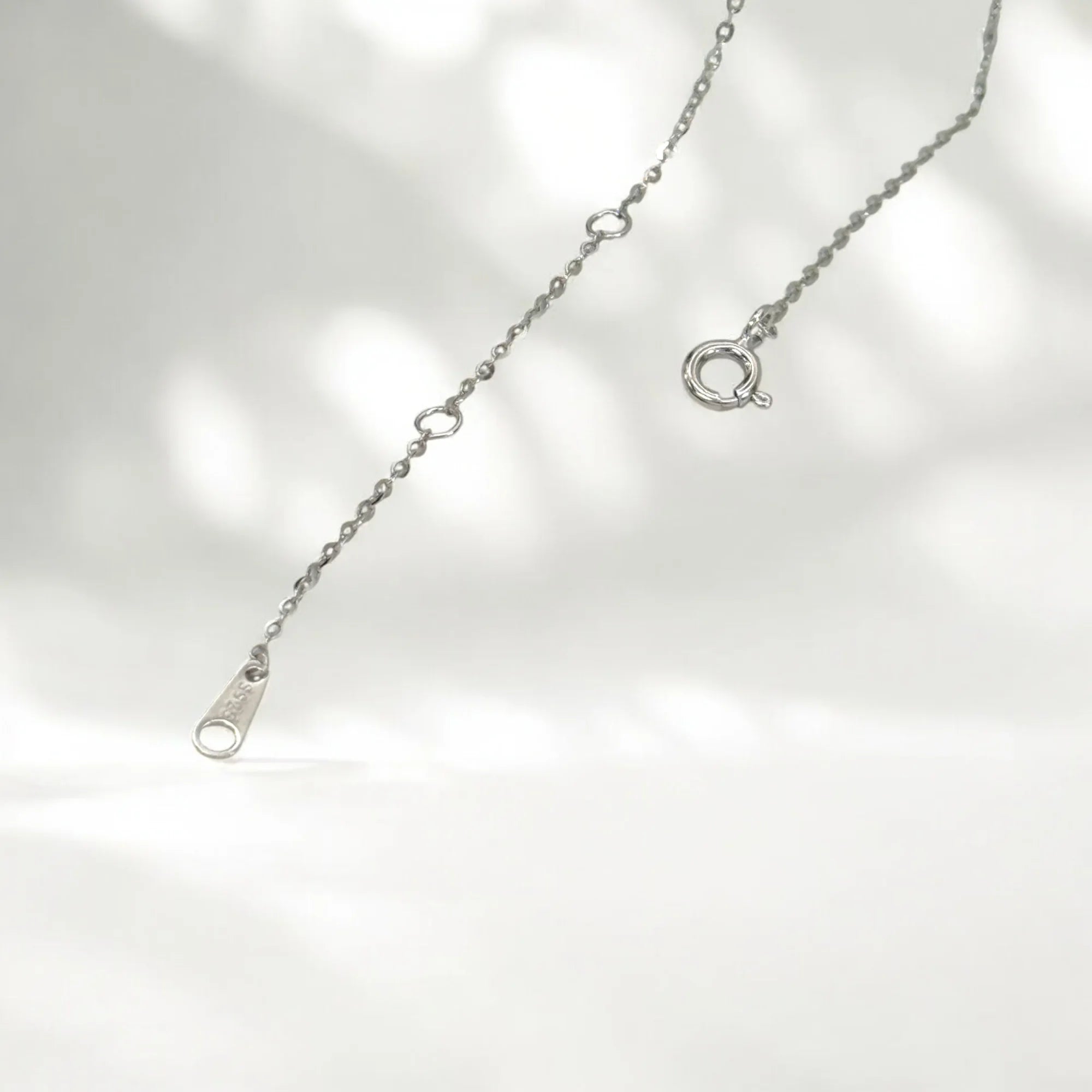Silver necklace with a clasp on a light gray background