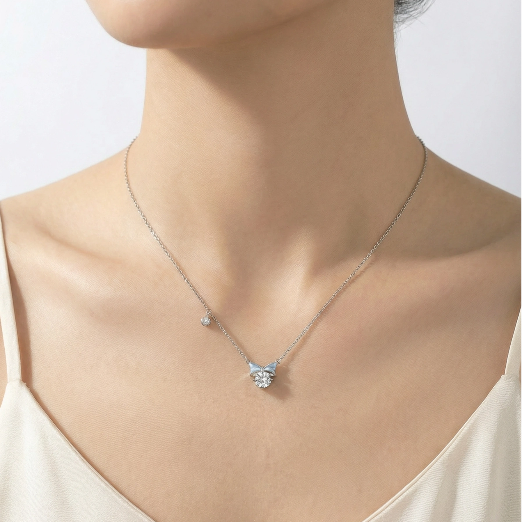 Model wearing blue enamel silver mini bow necklace at collarbone
