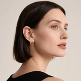 Model wearing hypoallergenic gold vermeil braided huggie hoop earrings
