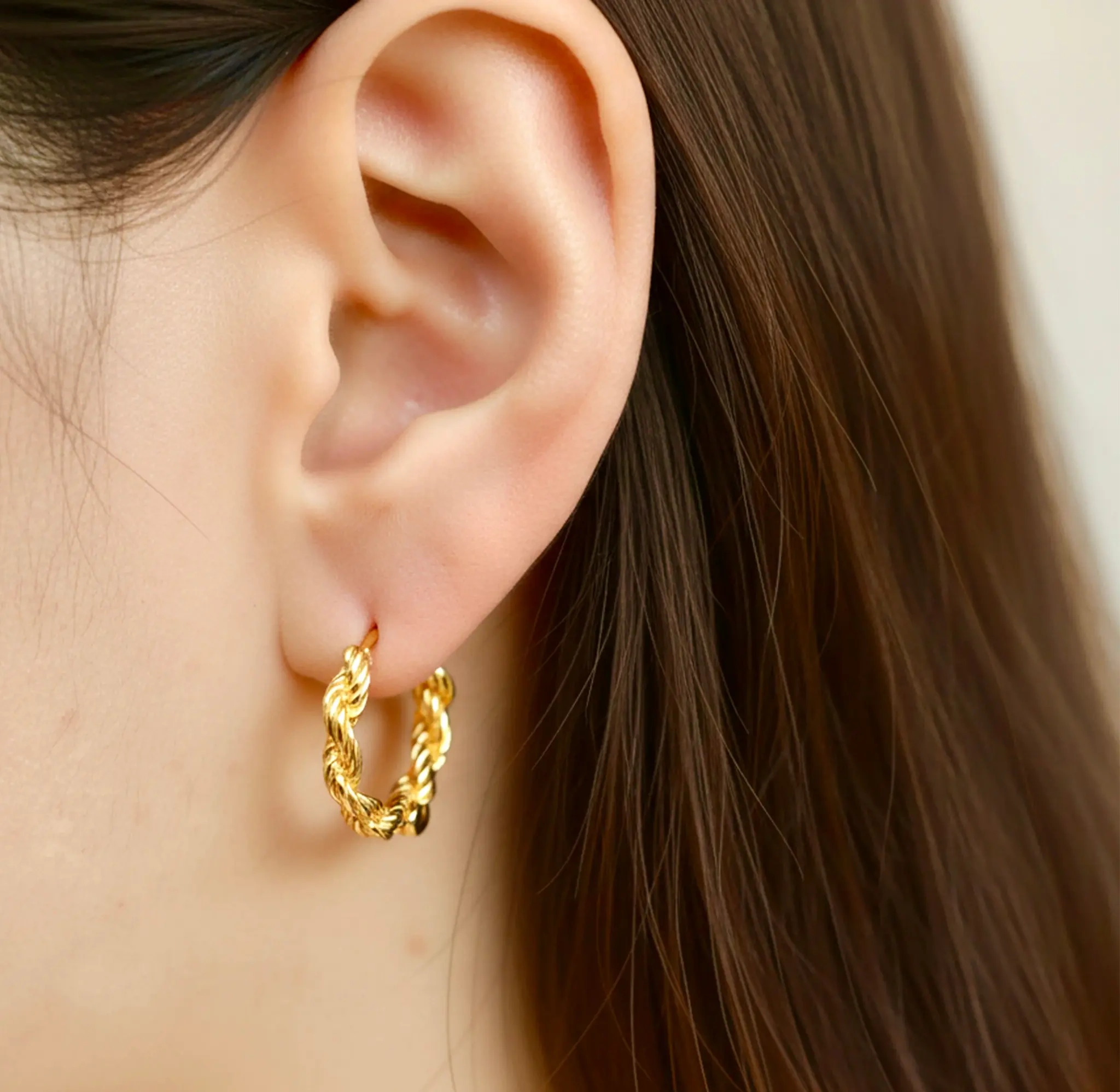 Model wearing hypoallergenic gold vermeil braided huggie hoop earrings
