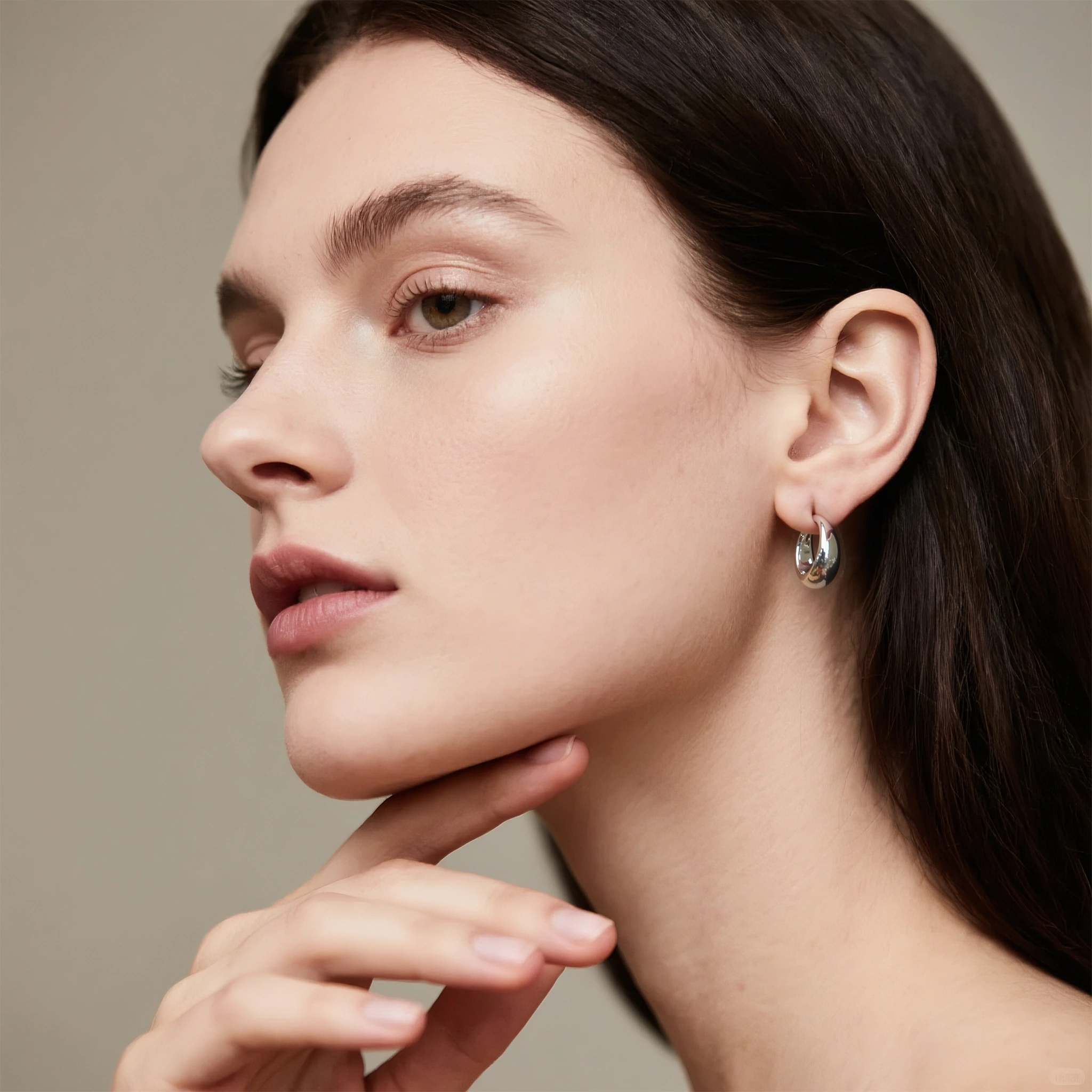 Model wearing hypoallergenic sterling silver eclipse dome huggie hoop earrings with rhodium vermeil
