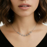 Close-up of a woman wearing a delicate silver necklace with floral designs.