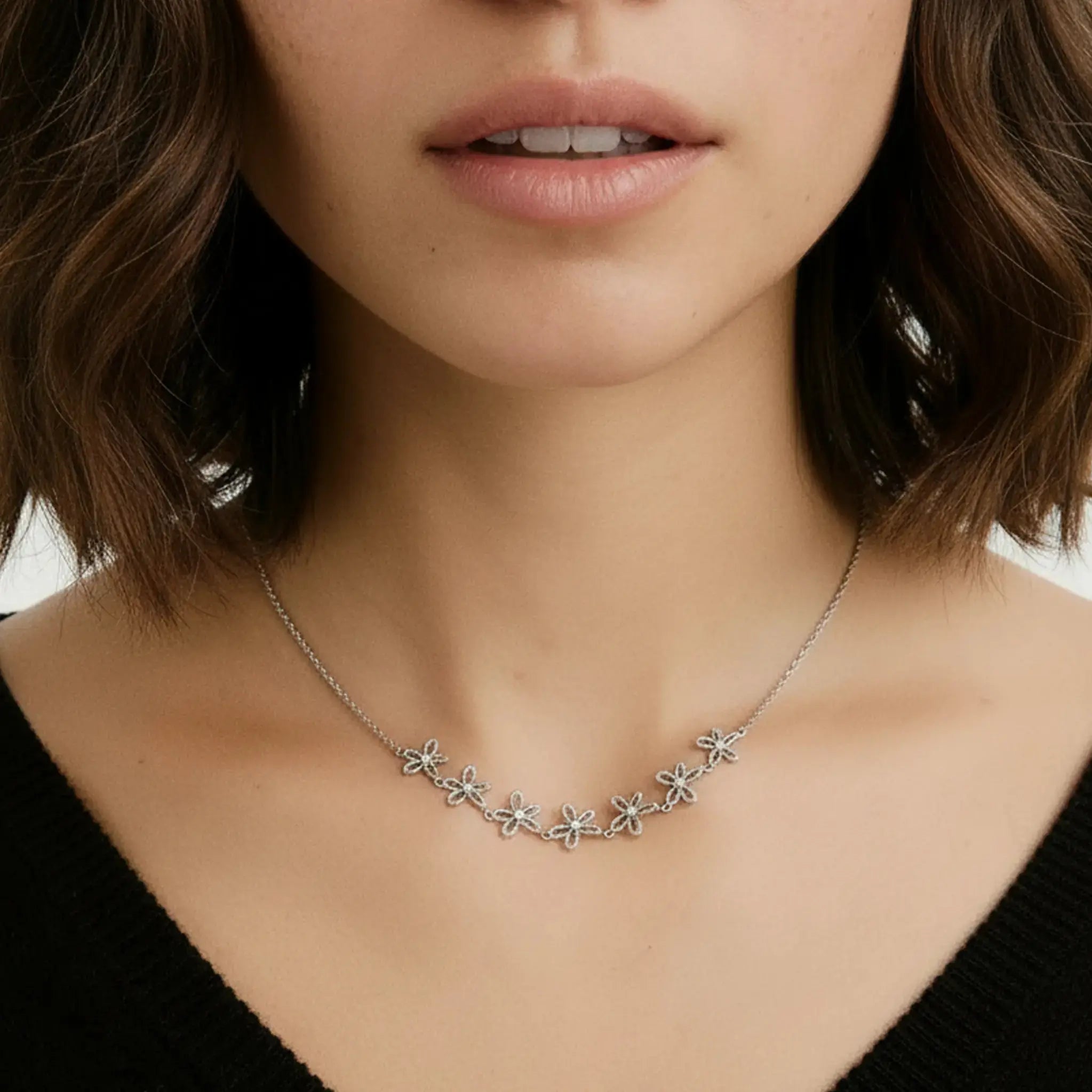 Close-up of a woman wearing a delicate silver necklace with floral designs.