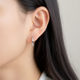 Close-up of an ear wearing a Petite geometric huggie hoops in sterling silver finish with pavé crystals