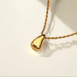 Gold necklace with a teardrop-shaped pendant on a light background