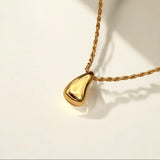 Gold necklace with a teardrop-shaped pendant on a light background