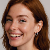Woman with red hair smiling against a plain background