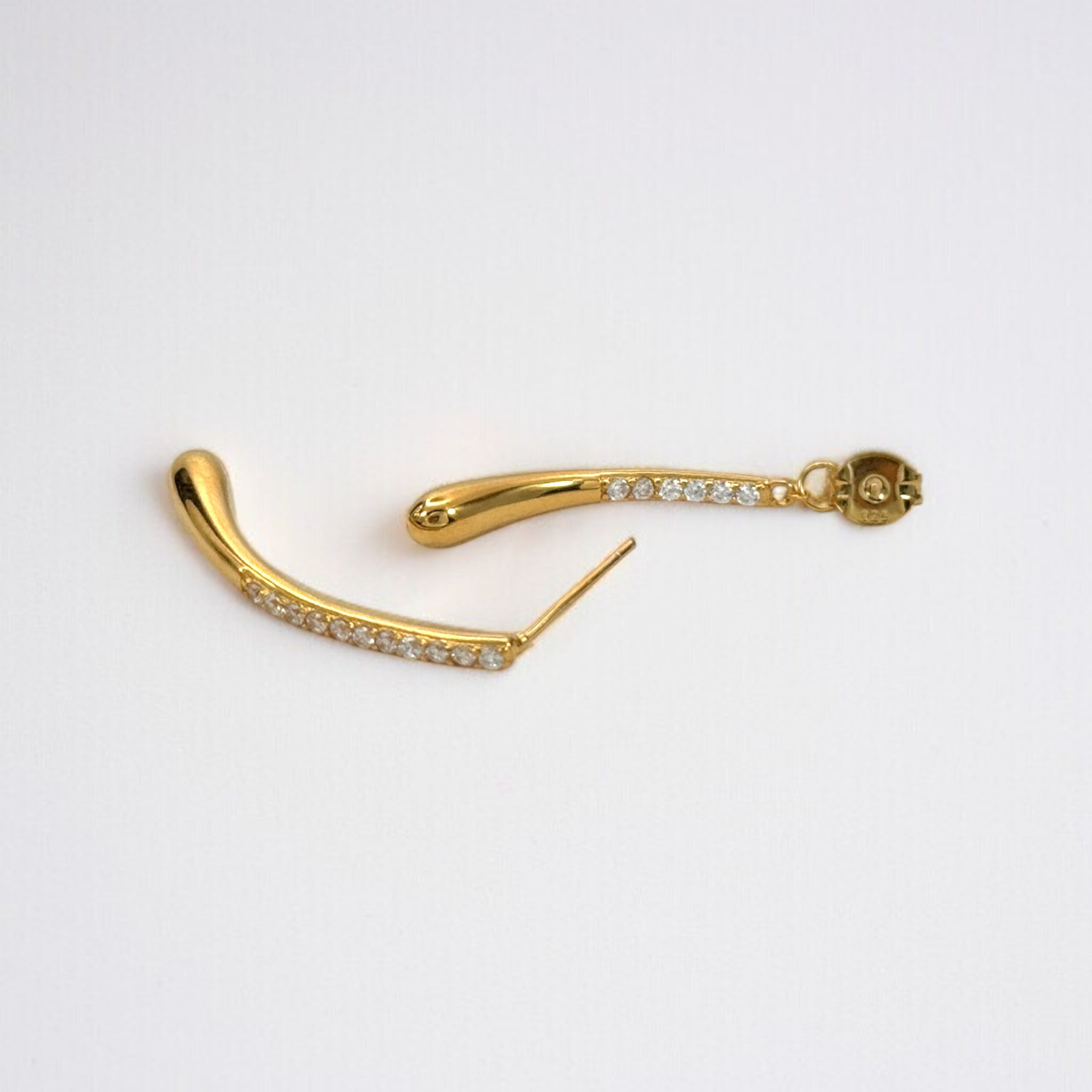 Close-up of Aurelia two-way gold pavé drop earrings showing curved double-drop silhouette and CZ pavé sparkle in 18K gold vermeil
