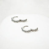 Close-up of Hermin's Tapered Baguette Silver Huggie Hoops in sterling silver with rhodium finish, crafted for elegance and durability