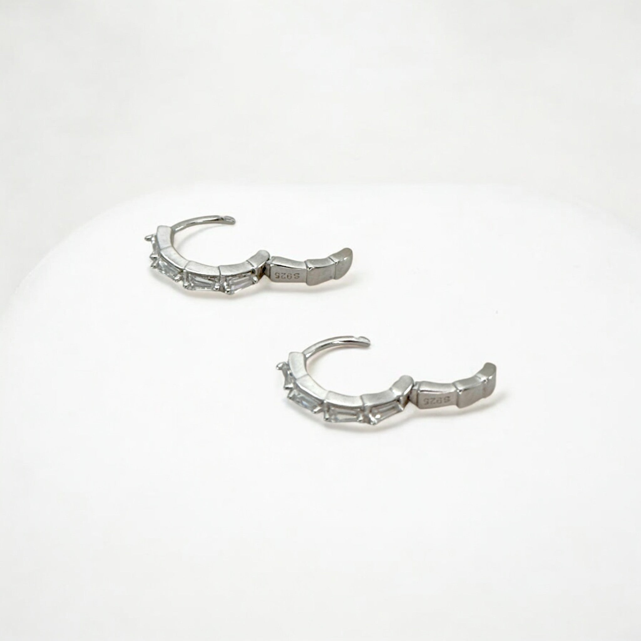 Close-up of Hermin's Tapered Baguette Silver Huggie Hoops in sterling silver with rhodium finish, crafted for elegance and durability
