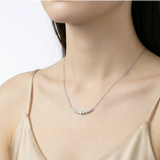Model wearing sterling silver crescent bar necklace with graduated moissanite stones