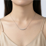Model wearing sterling silver crescent bar necklace with graduated moissanite stones