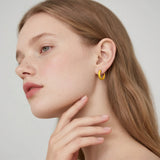 Close-up of a woman wearing a gold hoop earring against a neutral background