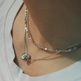 Model wearing hypoallergenic sterling silver tulle textured orb pendant necklace with rhodium vermeil
