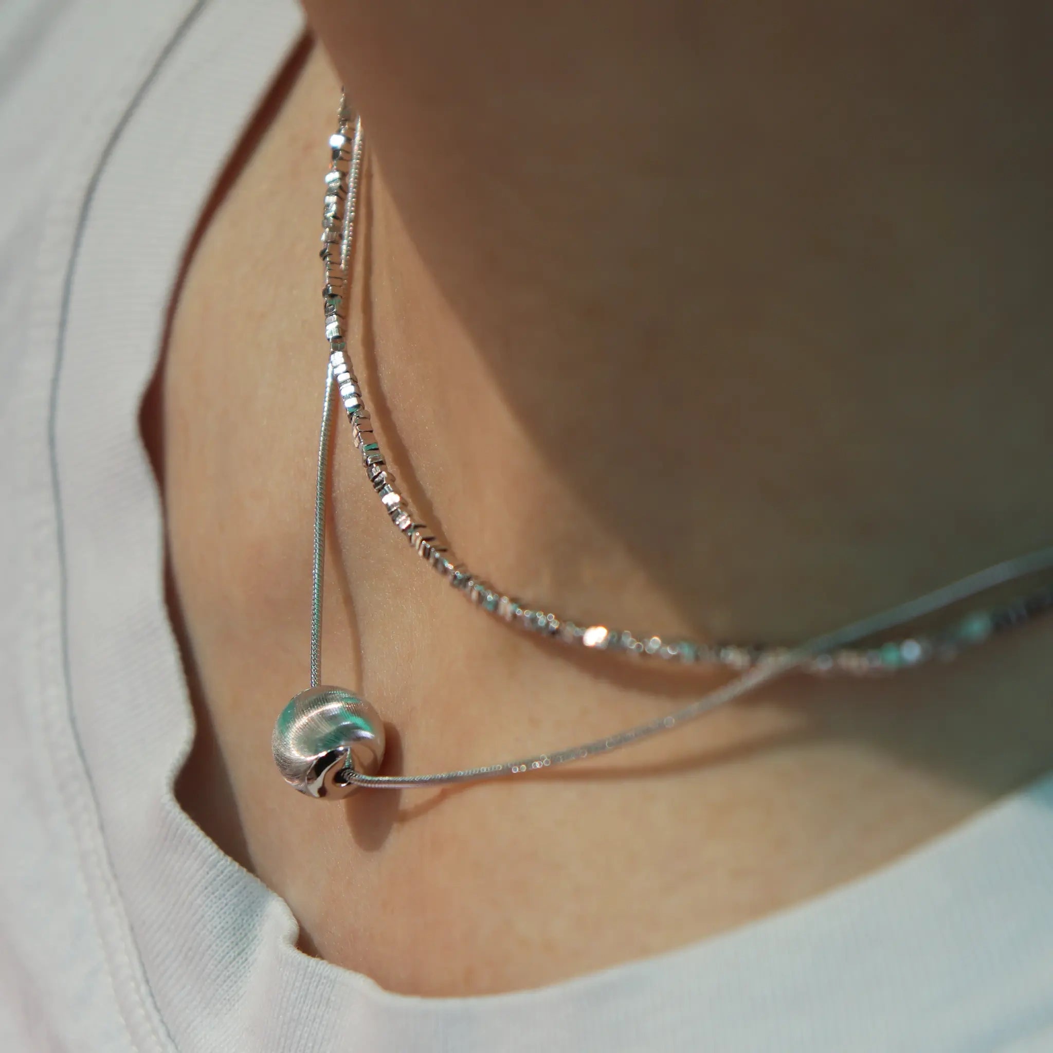 Model wearing hypoallergenic sterling silver tulle textured orb pendant necklace with rhodium vermeil
