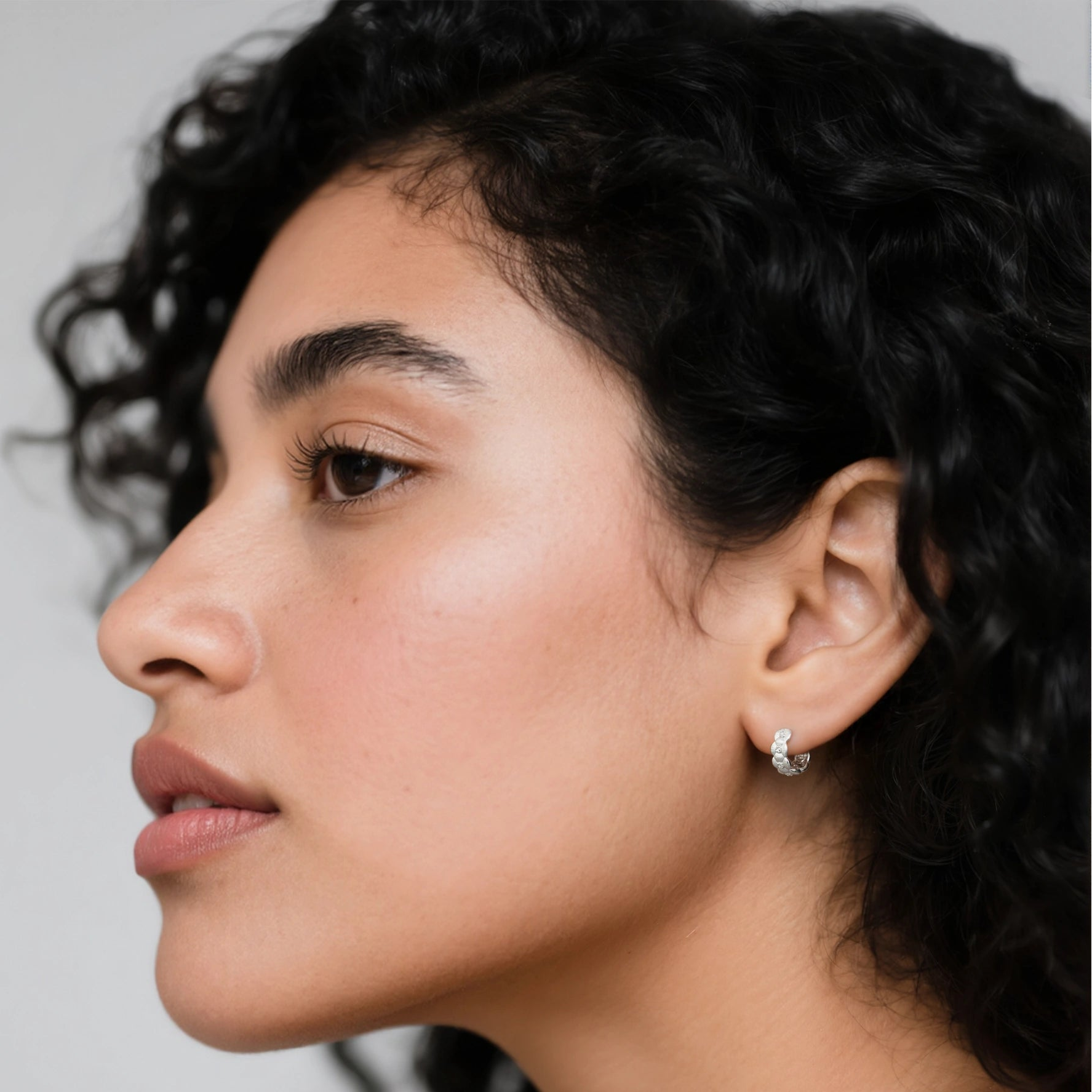 Model wearing hypoallergenic rhodium vermeil tulle textured woven sparkle huggie hoop earrings
