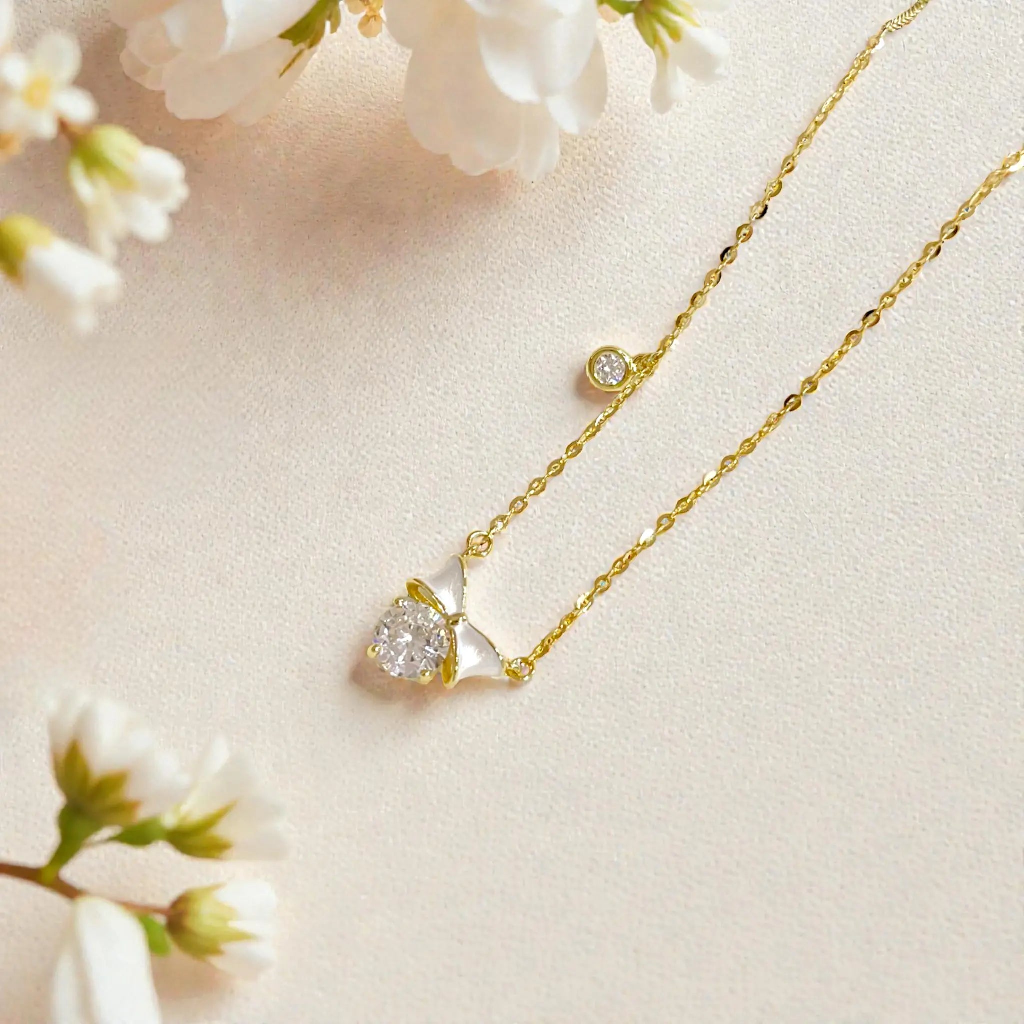 Gold petite bow pendant necklace with white enamel and crystals