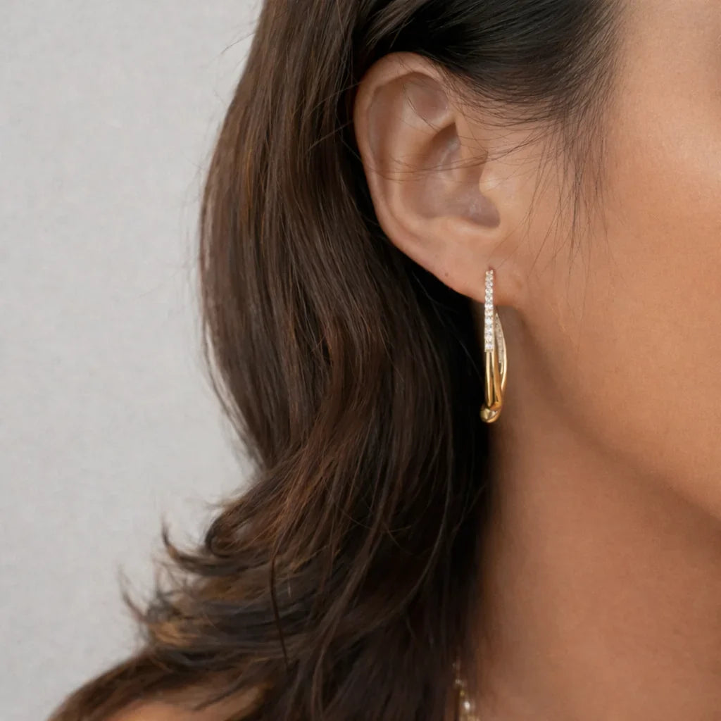Close-up of Aurelia two-way gold pavé drop earrings showing curved double-drop silhouette and CZ pavé sparkle in 18K gold vermeil