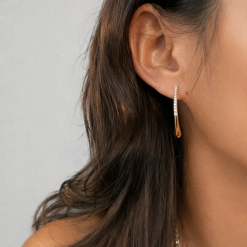 Close-up of Aurelia two-way gold pavé drop earrings showing curved double-drop silhouette and CZ pavé sparkle in 18K gold vermeil