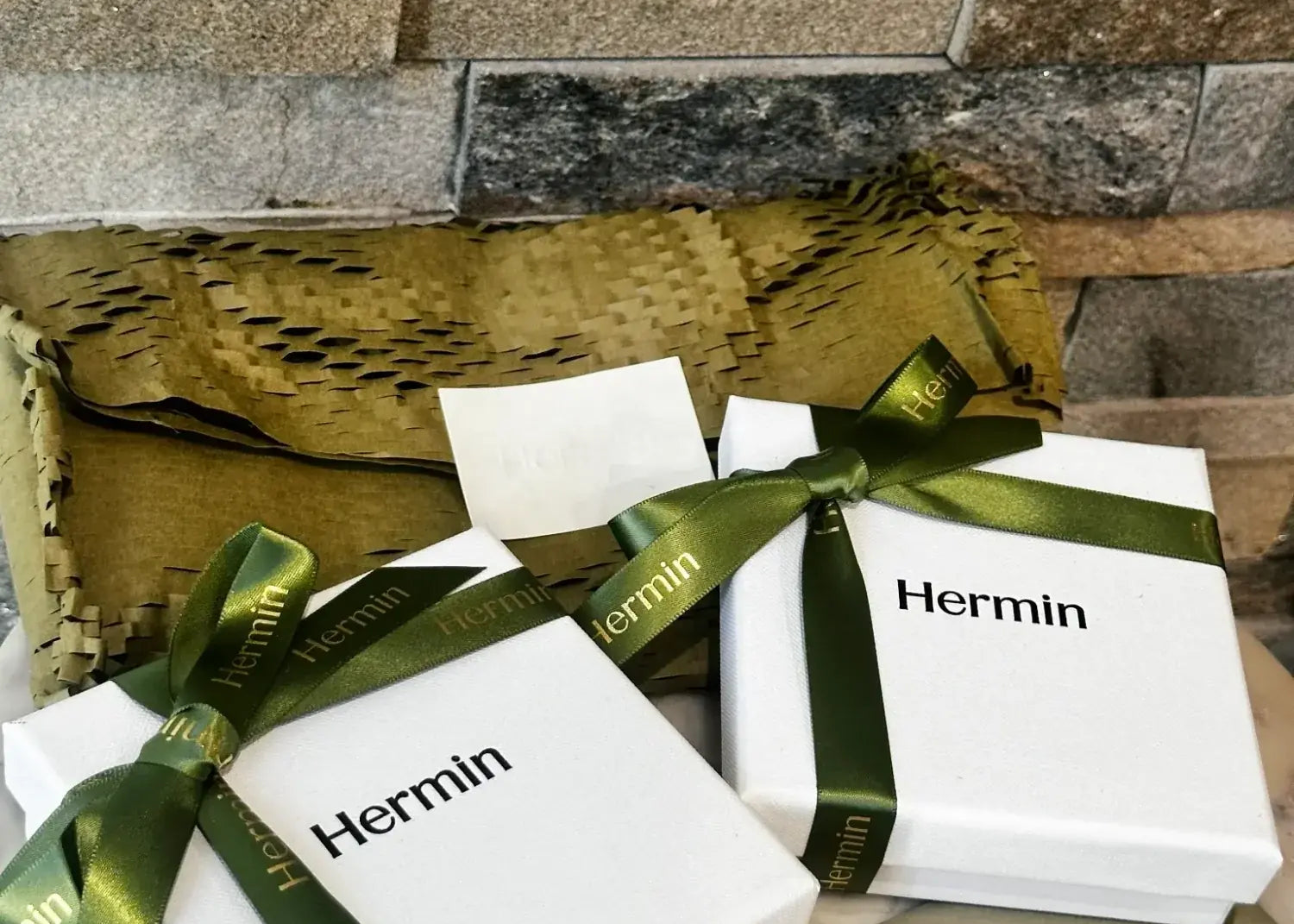White boxes with green ribbons labeled 'Hermin' presenting gift ready packaging with premium feel