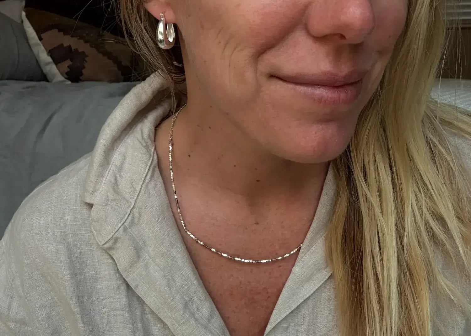 Woman wearing classic minimalist silver jewelry and linen shirt