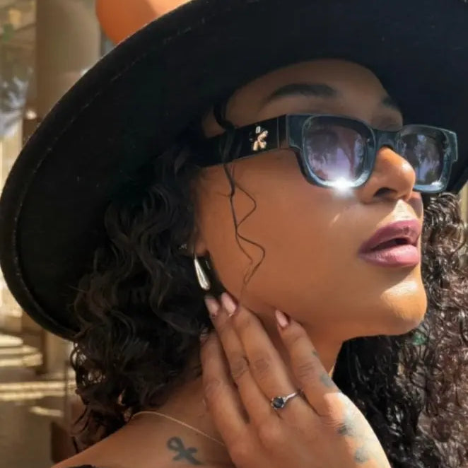 Woman wearing a black hat and sunglasses outdoors enjoying silver teardrop shaped earrings