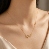 Gold necklace with a heart-shaped pendant on a person wearing a beige top.