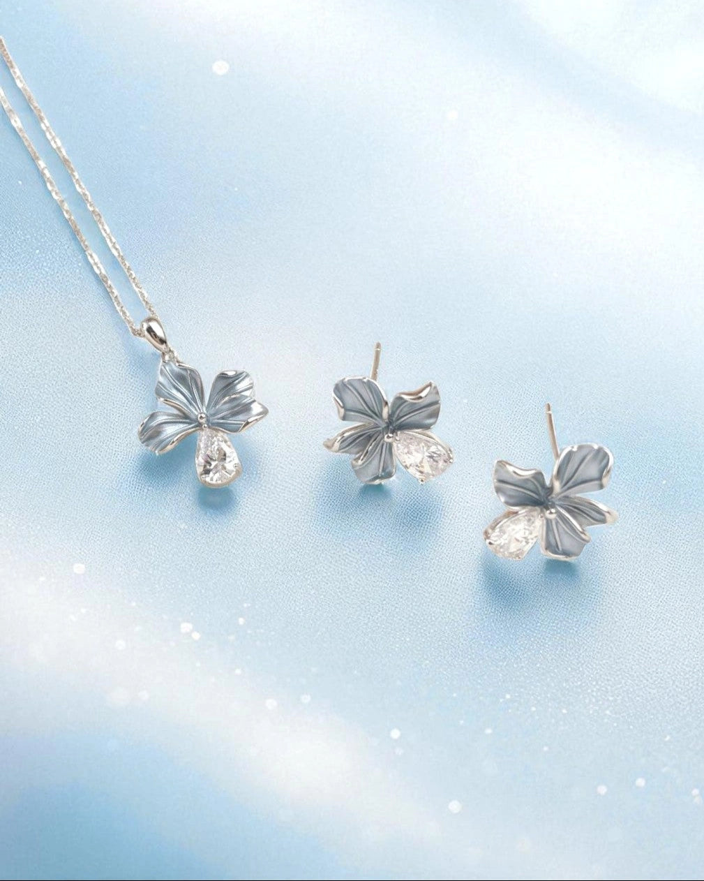 flower-shaped silver jewelry set on a light blue background